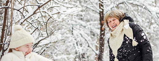 Image of senior woman playing in snow with young granddaughter